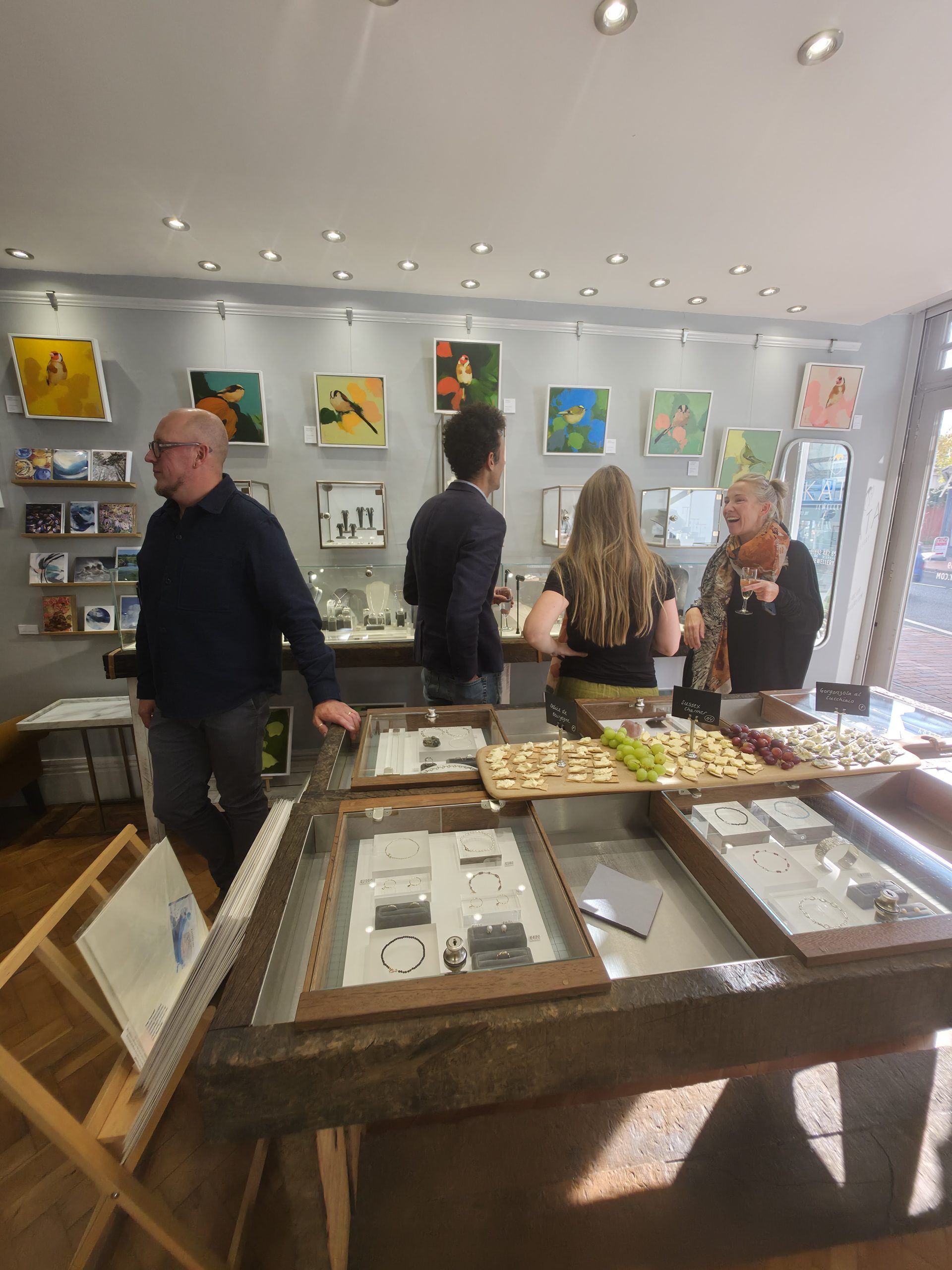 Visitors admiring Heidi Langridge's colourful bird paintings at KATA Jewellery's Meet the Artist exhibition.