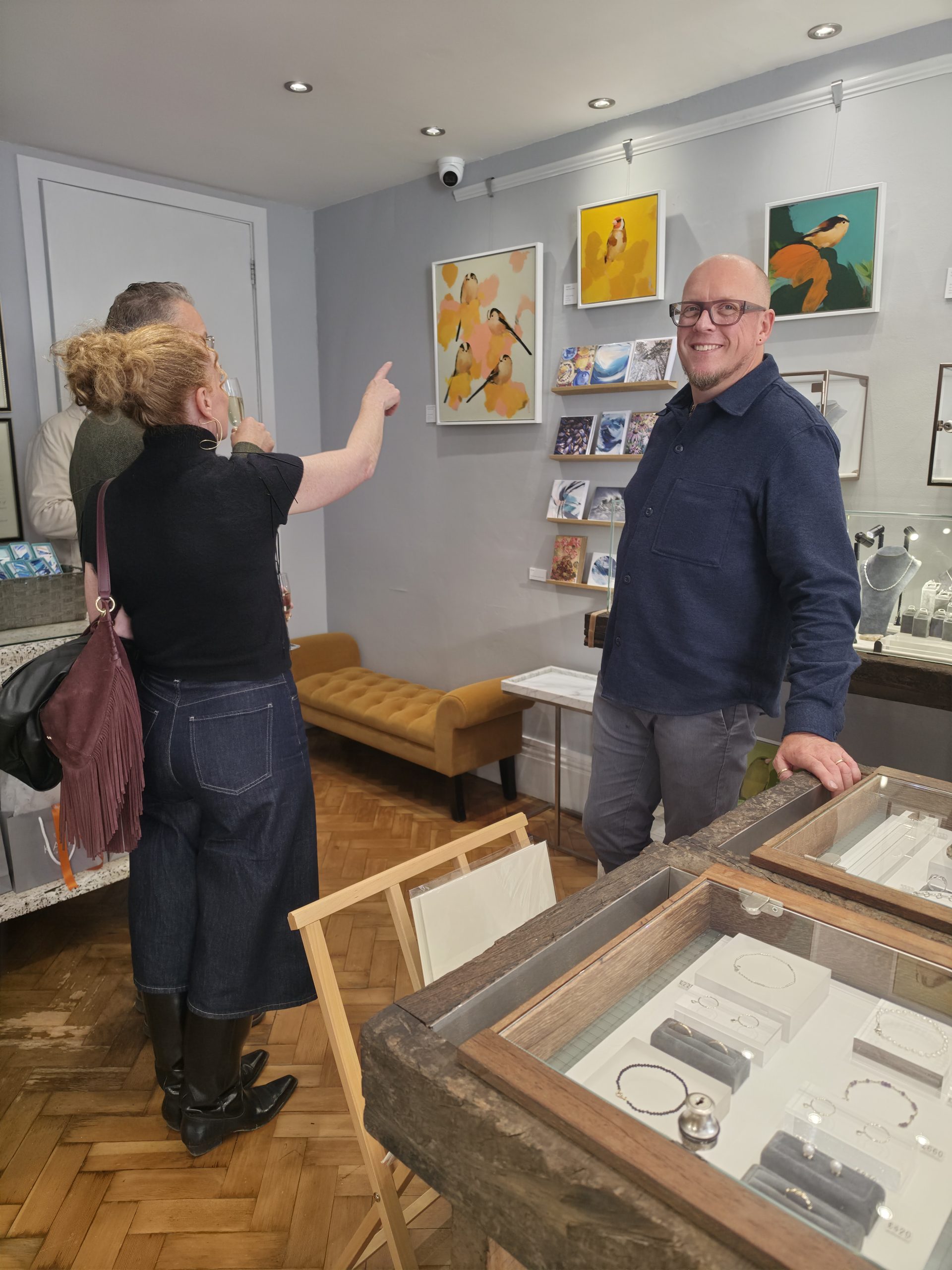 Guests discussing artwork beside the jewellery displays at KATA's Meet the Artist event in Tunbridge Wells.